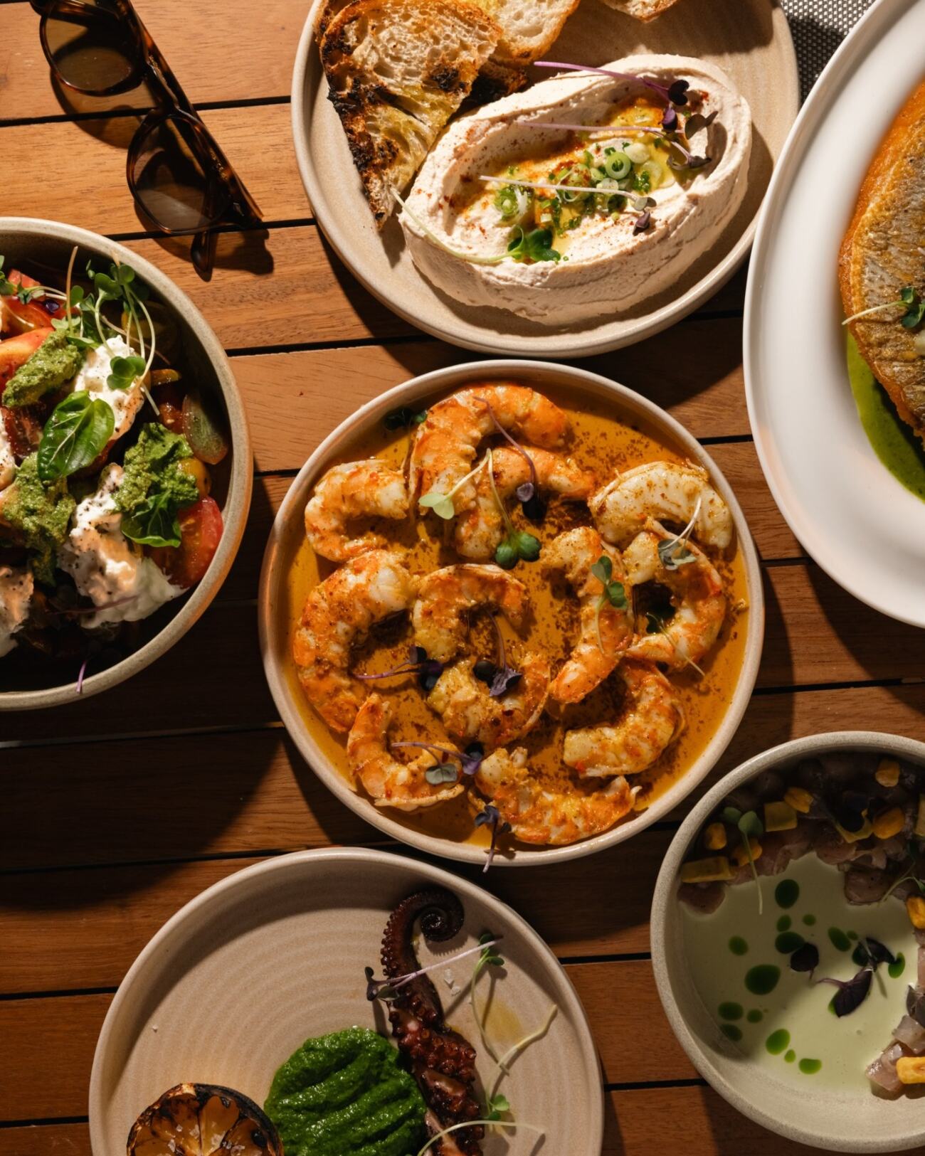 A spread of whipped labneh with charred sourdough, garlic chili shrimp, burrata and grilled octopus on the terrace table.